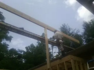 Carpenter setting a ridge beam over a new addition frame — Ice Dam Removal by Roofing Brothers in Swink
