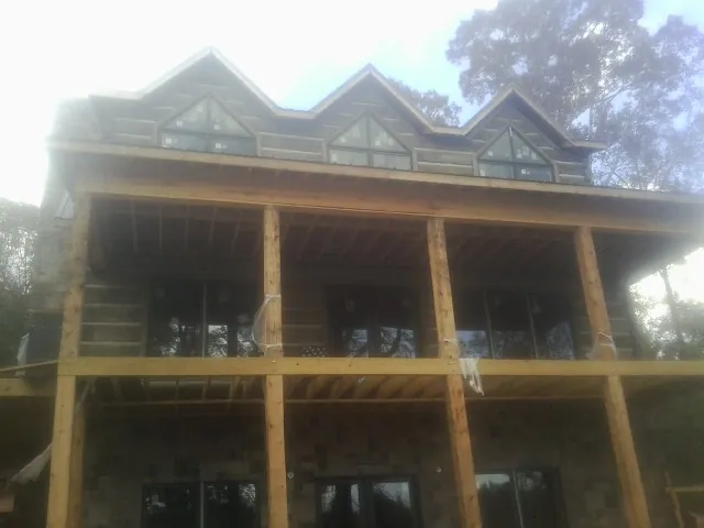Dormers and porch framing on a large log home under construction — Roof Coating work by our crew in Swink
