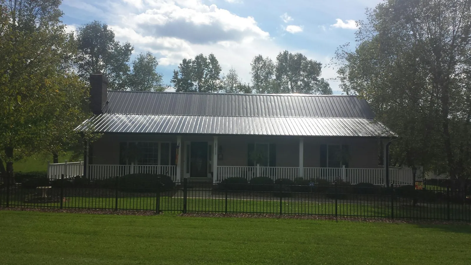 Gray metal roof on a brick ranch with a full width front porch — Gutter Guard Installation work by our crew in Swink