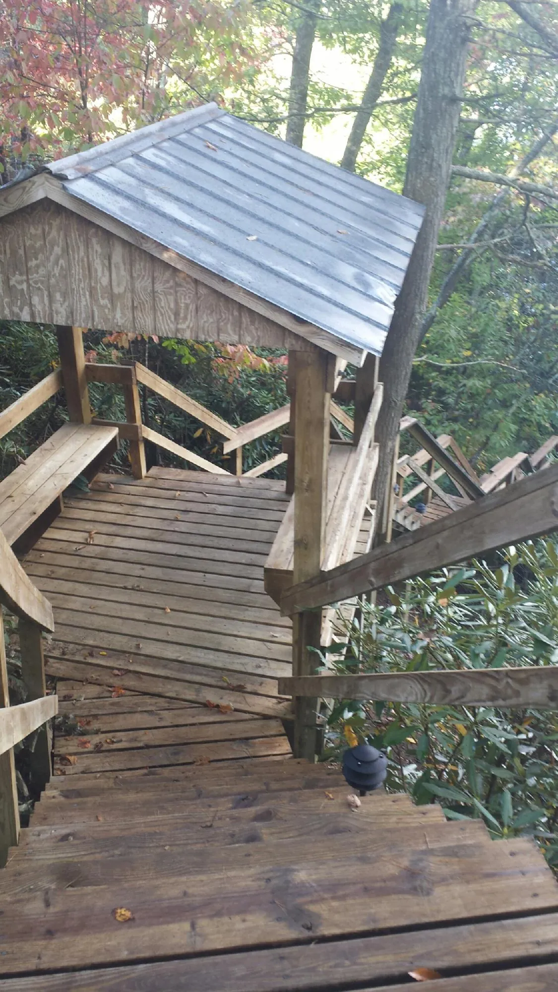 Metal roofed shelter over wooden steps on a wooded walkway — Skylight Repair & Installation work by our crew in Swink