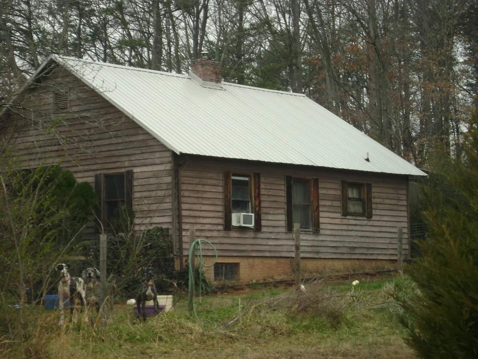 White metal roof on an old wood sided farmhouse, from a Metal Roof Installation job in Swink