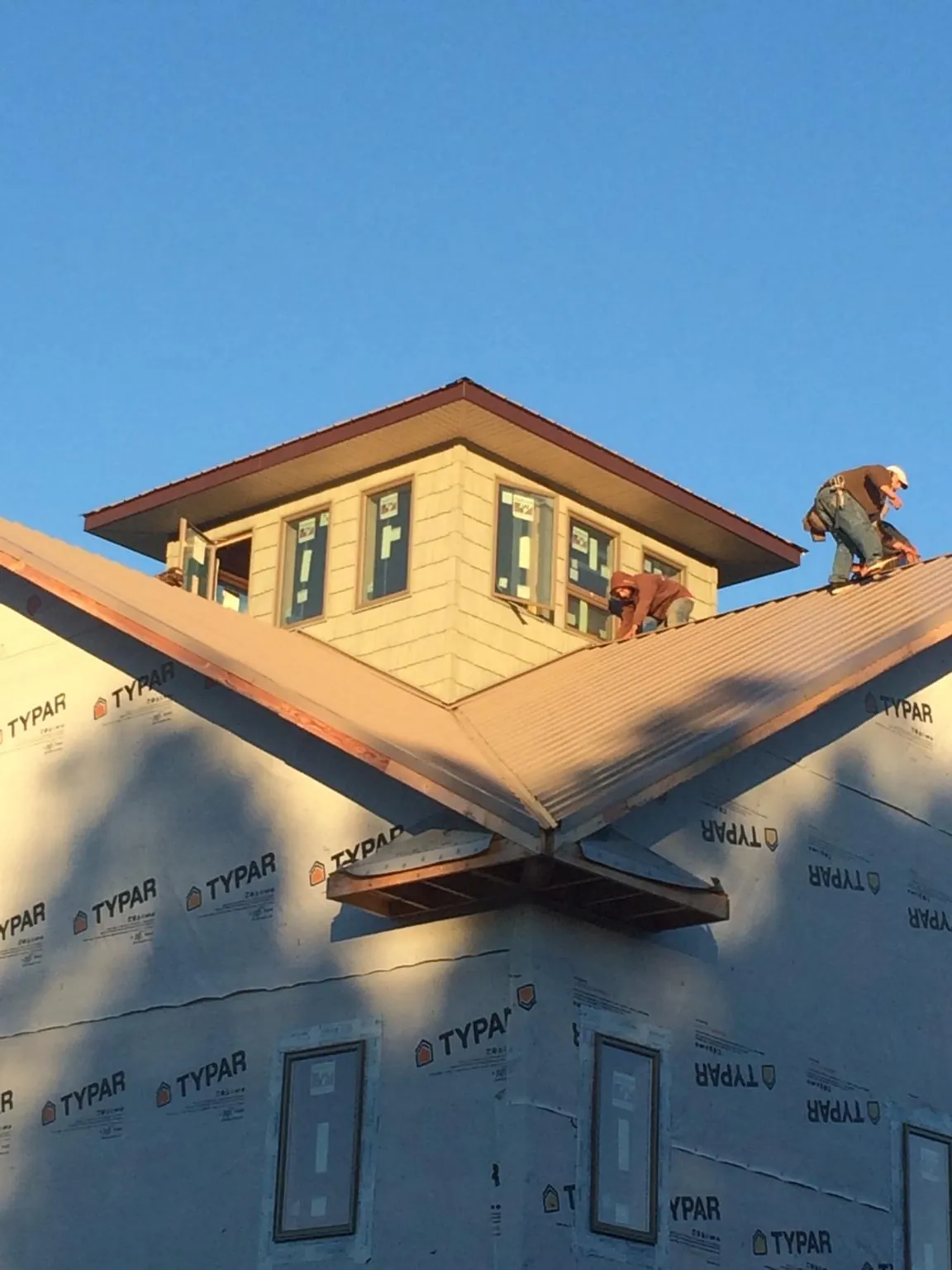Roofers working around a rooftop cupola on a new metal roof at sunset — Roof Waterproofing in Swink by Roofing Brothers